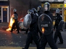 riot police marching down street fire behind from side 1024x768