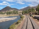 trains rail tracks next to river through hills with blue sky p1010120 b
